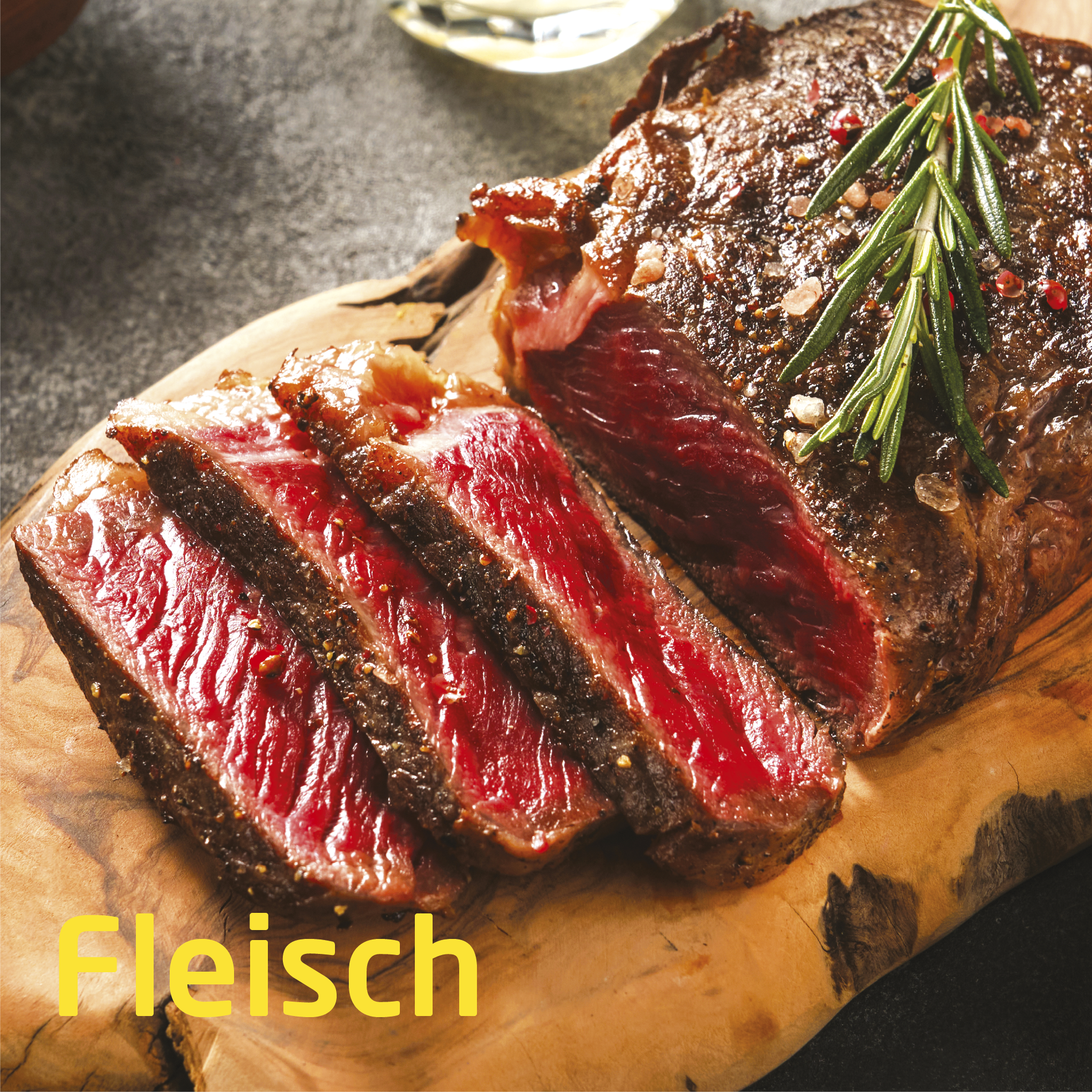 Geschnittenes, gebratenes Steak auf einem Holzbrett. Das Fleisch ist rot mit dunkler Kruste. Rosmarinzweig und Salz.