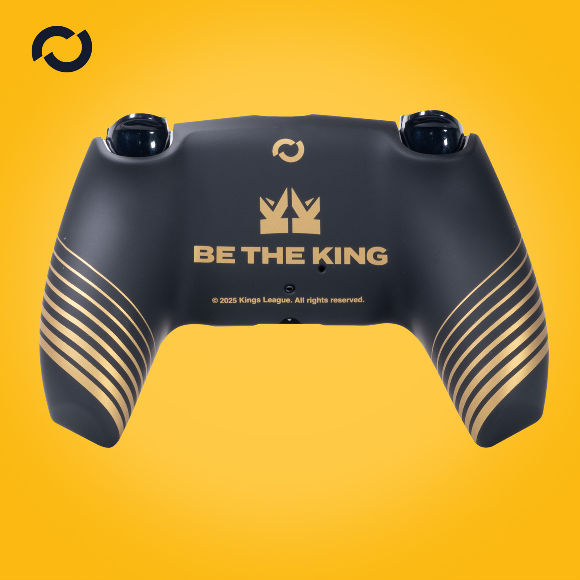 Fekete játékvezérlő arany díszítéssel és a 'BE THE KING' felirattal sárga háttéren. A logó látható.