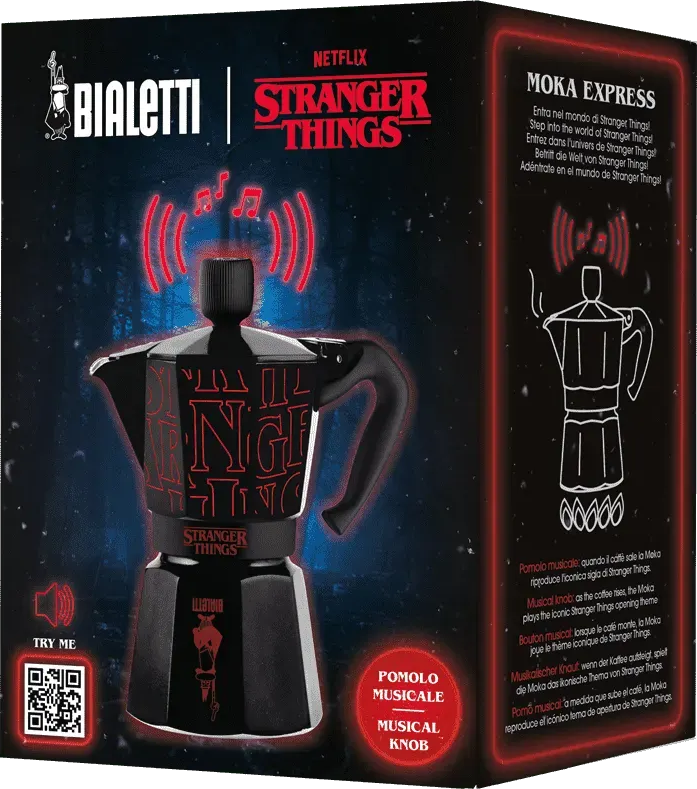 Fekete Bialetti Moka kávéfőző Stranger Things logóval, zenei gombbal, piros részletekkel, hanghullám szimbólumokkal.