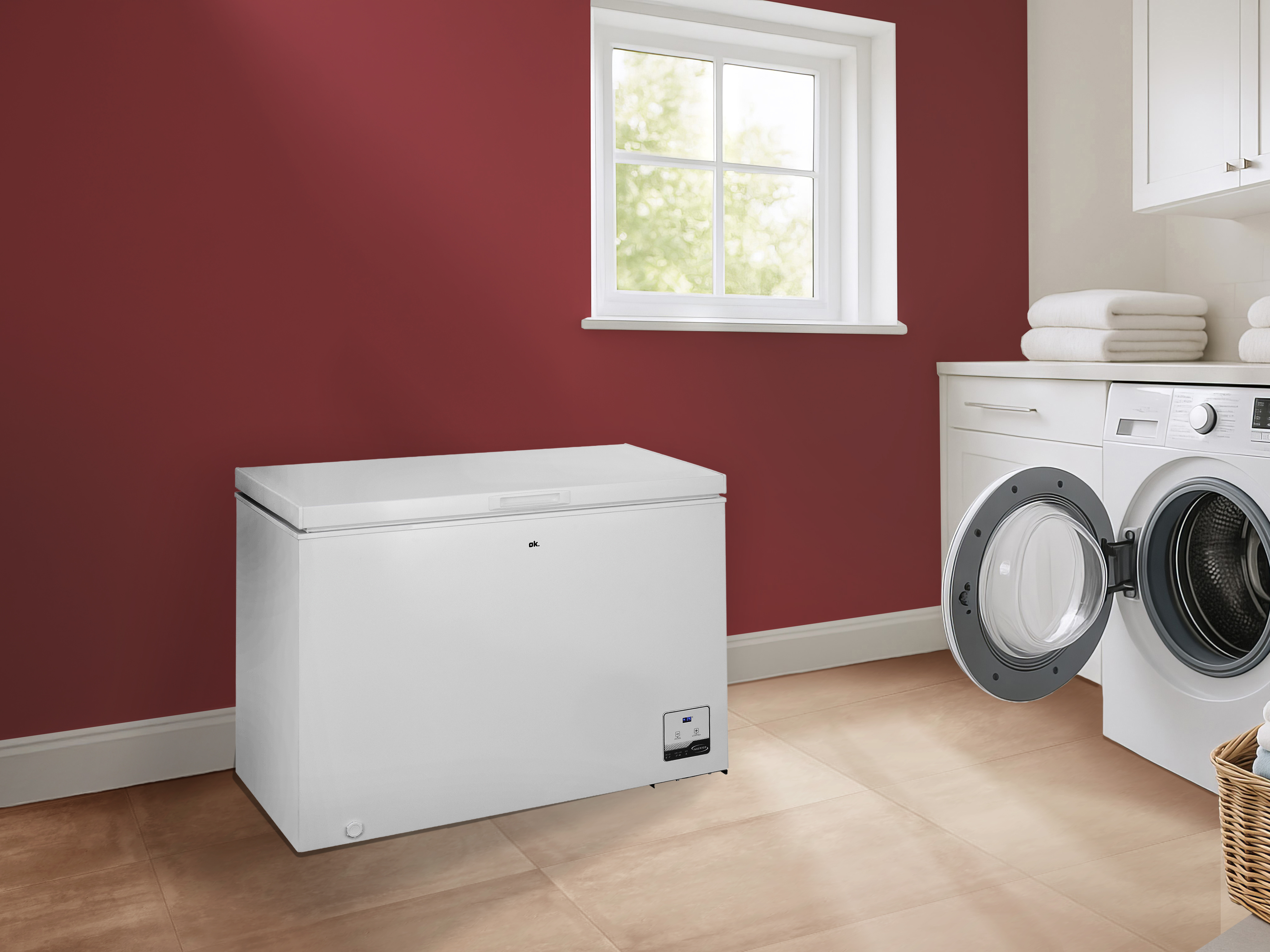 Ein weißer Gefrierschrank steht in einem Waschraum mit Waschmaschine, Fenster und roter Wand.