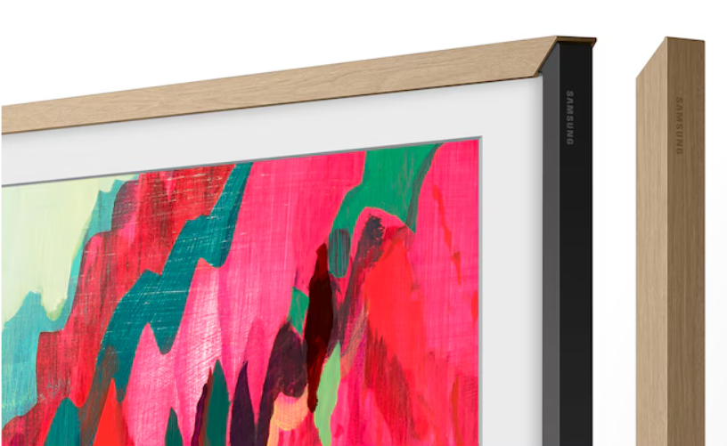 Telewizor Samsung Frame z jasną drewnianą ramą. Ekran wyświetla kolorowy obraz abstrakcyjny. Odrębny kawałek drewna po prawej.