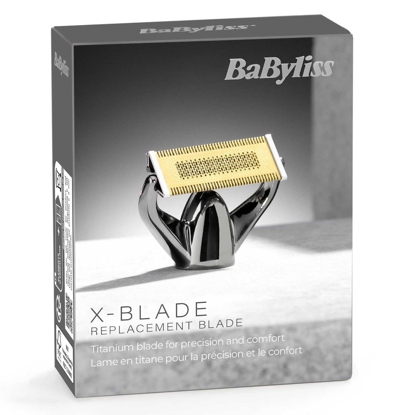 A képen egy BaByliss X-Blade cserélhető penge látható. Arany pengével, ezüst állvánnyal és fekete dobozzal rendelkezik.