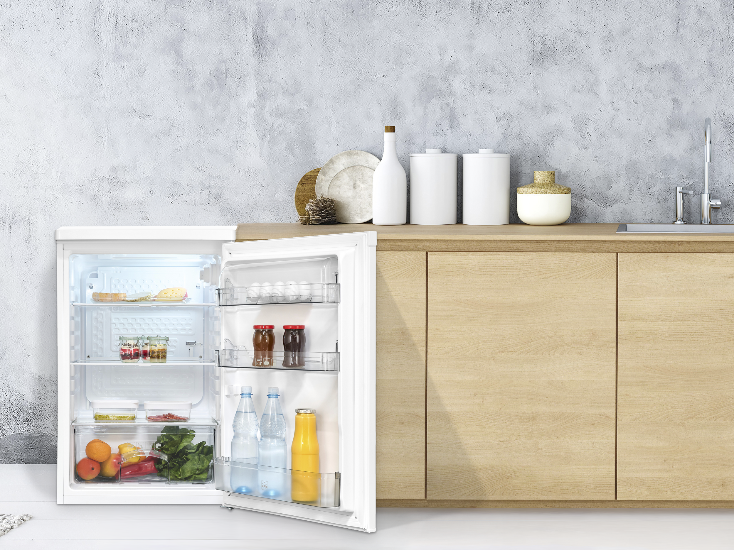 Offener Kühlschrank mit Lebensmitteln. Gläser, Käse, Obst und Gemüse sind sichtbar. Weiße Flaschen und Gläser auf der Theke.