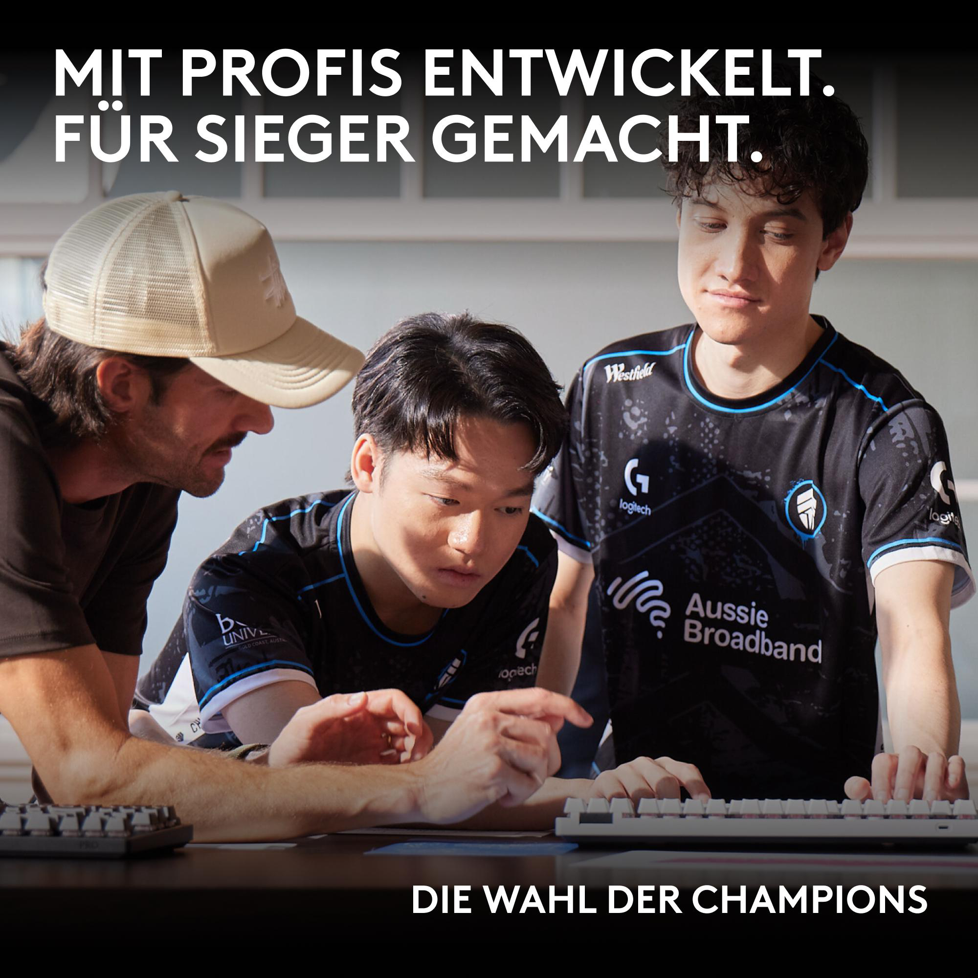 Drei E-Sportler betrachten eine Tastatur. Ein Mann trägt eine Kappe. Text lautet 'Die Wahl Der Champions'.