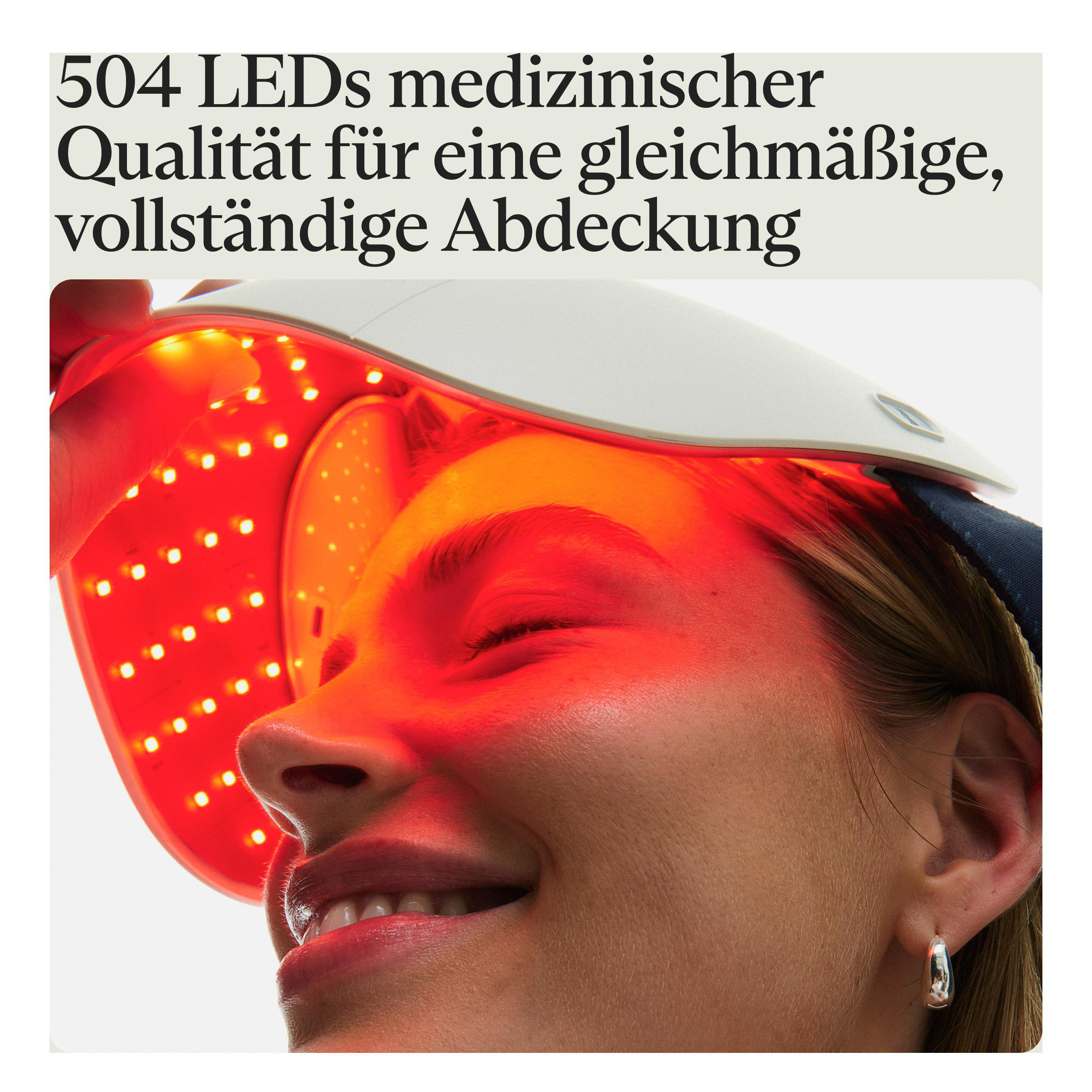 Eine Frau trägt eine rote LED-Maske. Die Maske hat viele kleine Lichter. Ihr Gesicht wird von dem roten Licht beleuchtet.