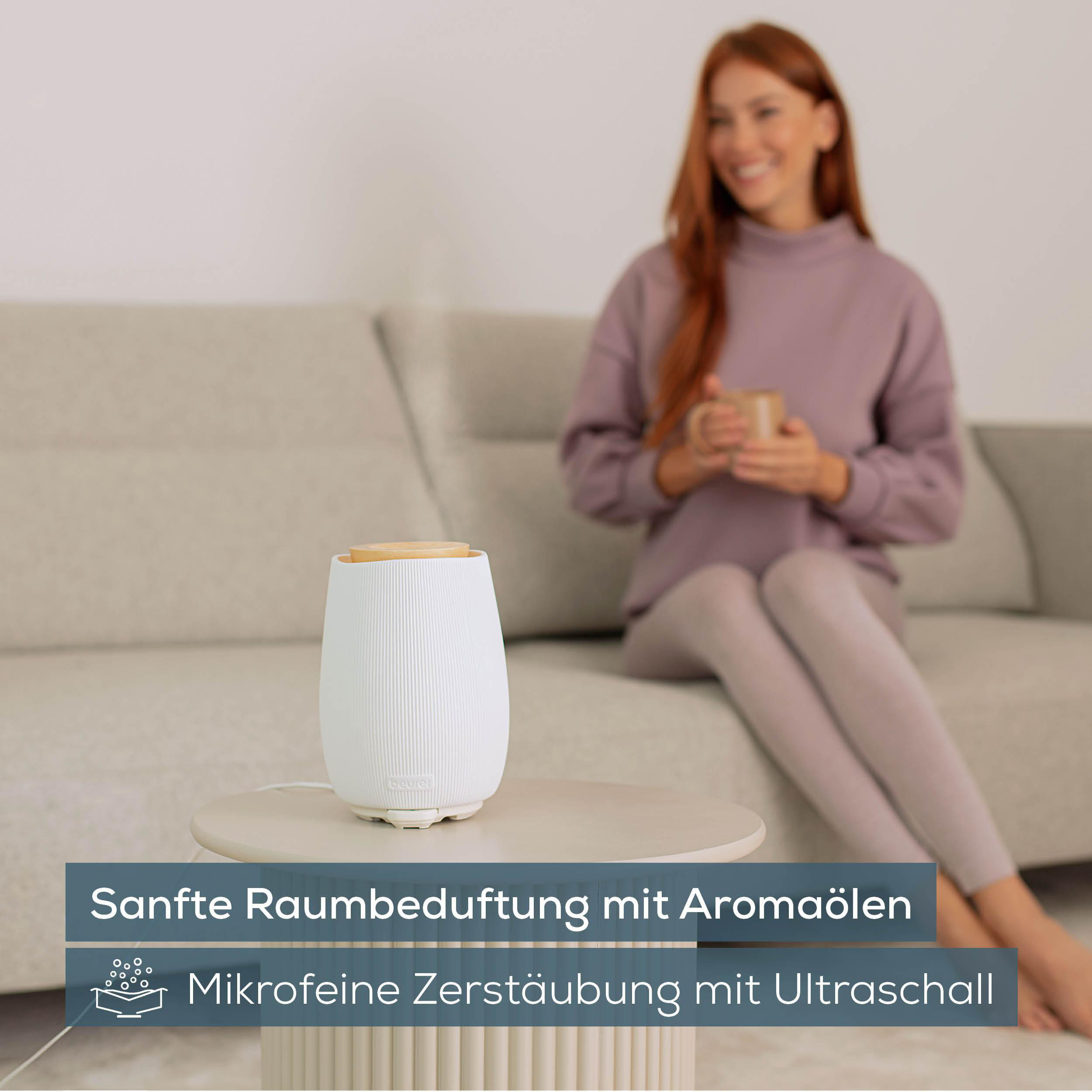 Aromadiffusor auf Tisch. Frau im Hintergrund mit Tasse. Text: Sanfte Raumbeduftung mit Aromaölen.