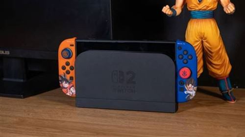Consola Nintendo Switch con mandos naranja y azul, una figura de un personaje con ropa naranja está detrás.