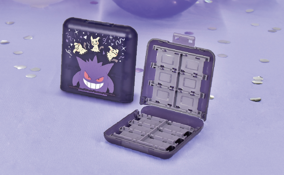 Offene lila Hülle mit Gengar- und Mimikyu-Designs. Die Hülle ist geöffnet und zeigt Schlitze. Lila Konfetti liegt auf dem Tisch verstreut.