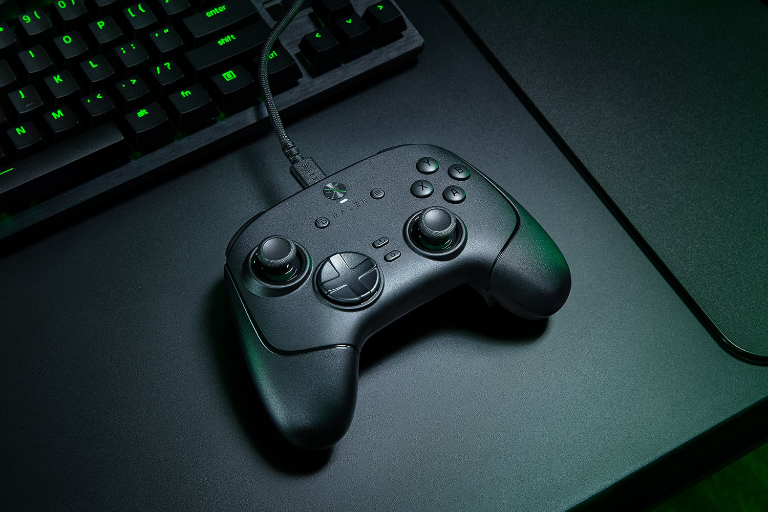 Controller di gioco Razer nero con pulsanti, joystick e tastiera sullo sfondo su una superficie nera.