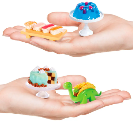 Hände halten Miniatur-Lebensmittel: Sushi, blauer Geleedessert, Kuchen und einen Taco in einem Dinosaurierhalter, vor weißem Hintergrund.