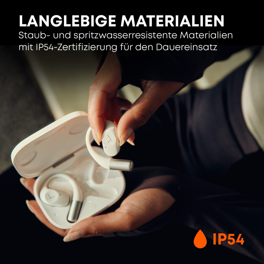 Eine Person hält einen weißen Ohrhörer mit silbernem Stiel in der Nähe eines offenen Gehäuses. Text oben: langlebige Materialien, IP54 zertifiziert.