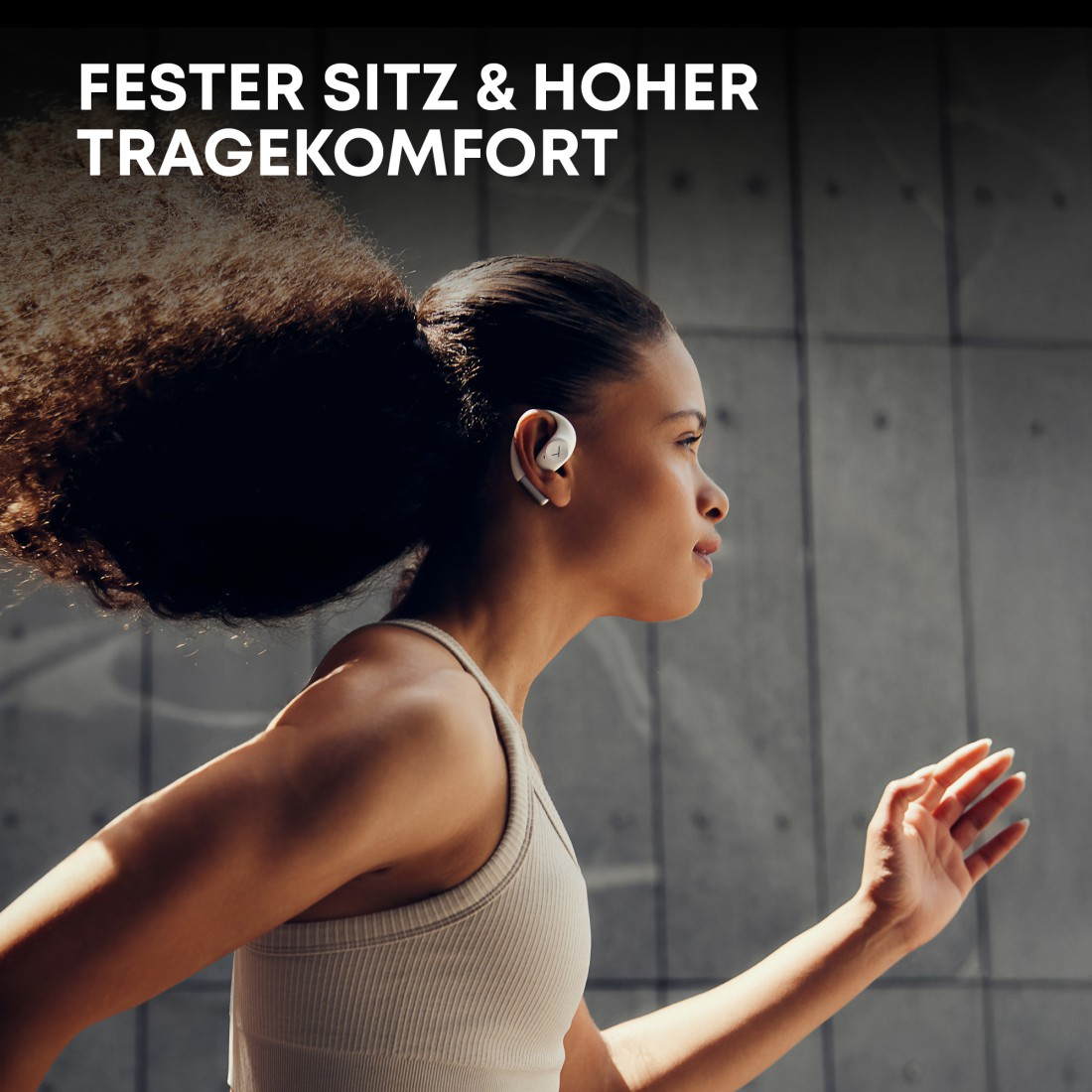 Eine Frau rennt mit Ohrhörern, trägt ein beiges Tanktop. Der Hintergrund ist eine graue Betonmauer. Text: 'Fester Sitz & hoher Tragekomfort'.