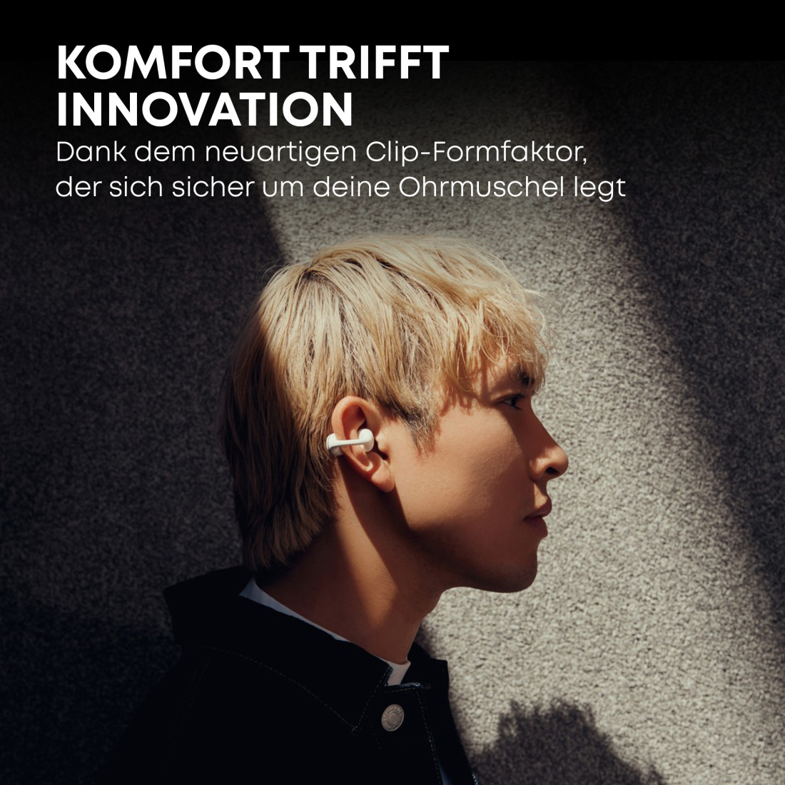 Ein Mann mit blonden Haaren, der Ohrhörer trägt und nach rechts blickt. Text: 'KOMFORT TRIFFT INNOVATION'.