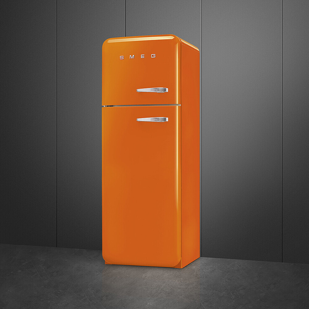 Ein orangefarbener Smeg-Kühlschrank. Er hat eine abgerundete Oberseite, zwei Türen mit Chromgriffen und steht vor einer dunkelgrauen Wand.