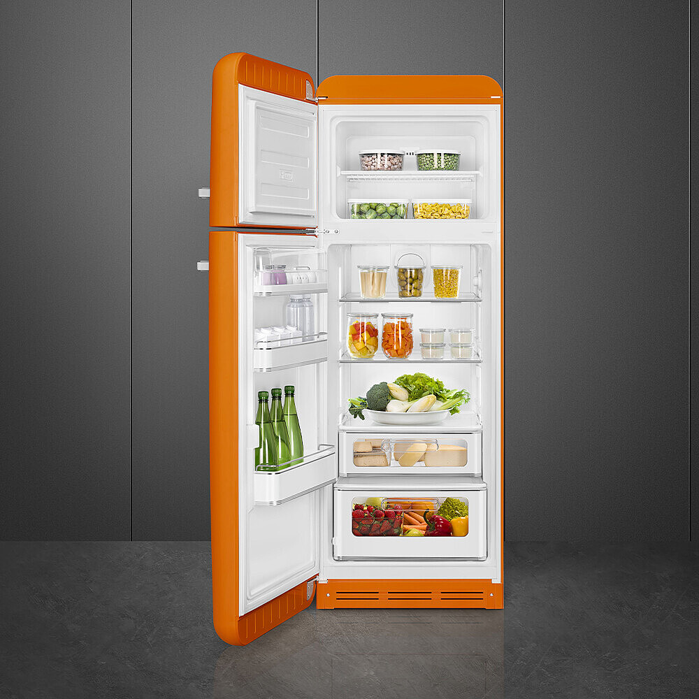 Ein offener, orangefarbener Kühlschrank mit Lebensmitteln gefüllt: Gemüse, Obst und Gläser mit Zutaten. Der Hintergrund ist eine graue Wand und ein grauer Boden.