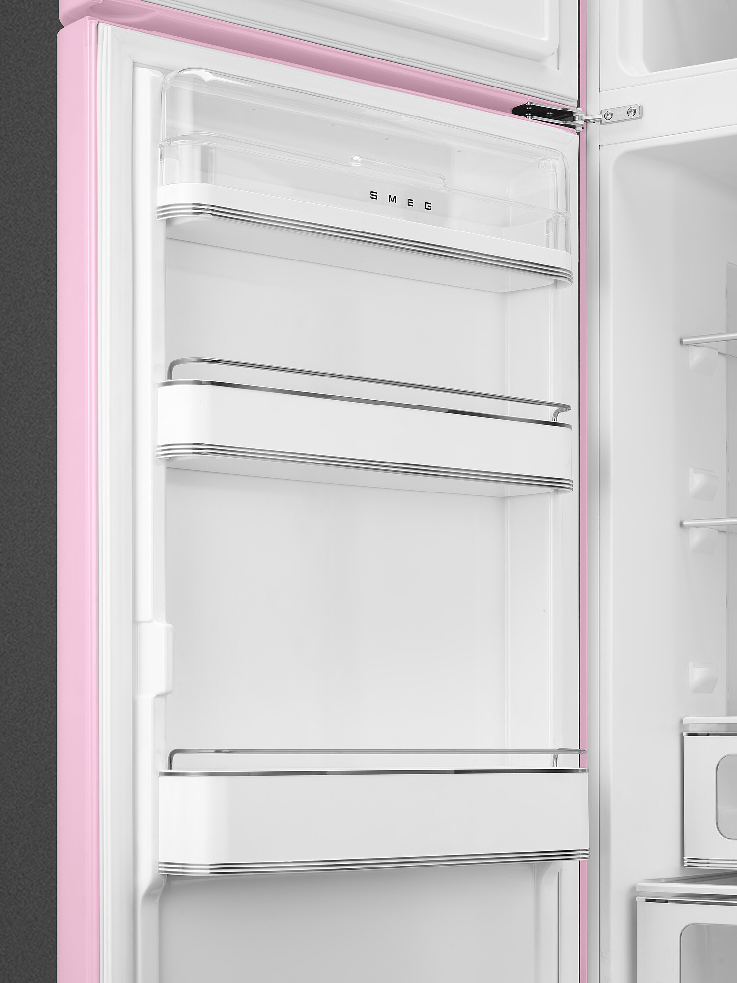 Offener rosa Smeg-Kühlschrank. Innenraum mit weißen Regalen, transparenten Schubladen und dem Markennamen SMEG. Rosa Rahmen und grauer Hintergrund.