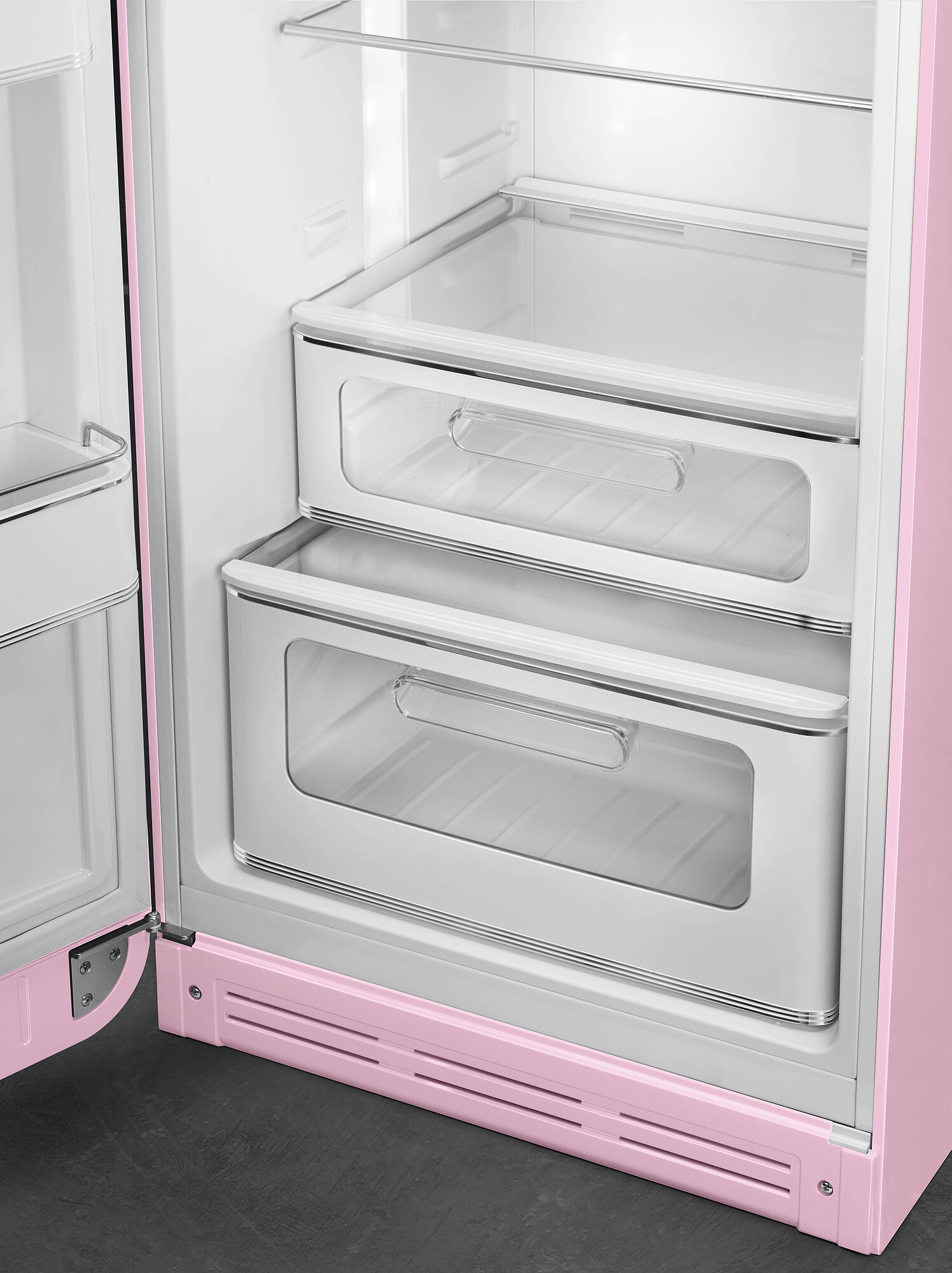 Offener rosa Kühlschrank. Zwei transparente Schubladen, weiße Regale und rosa Tür. Dunkelgrauer Boden.