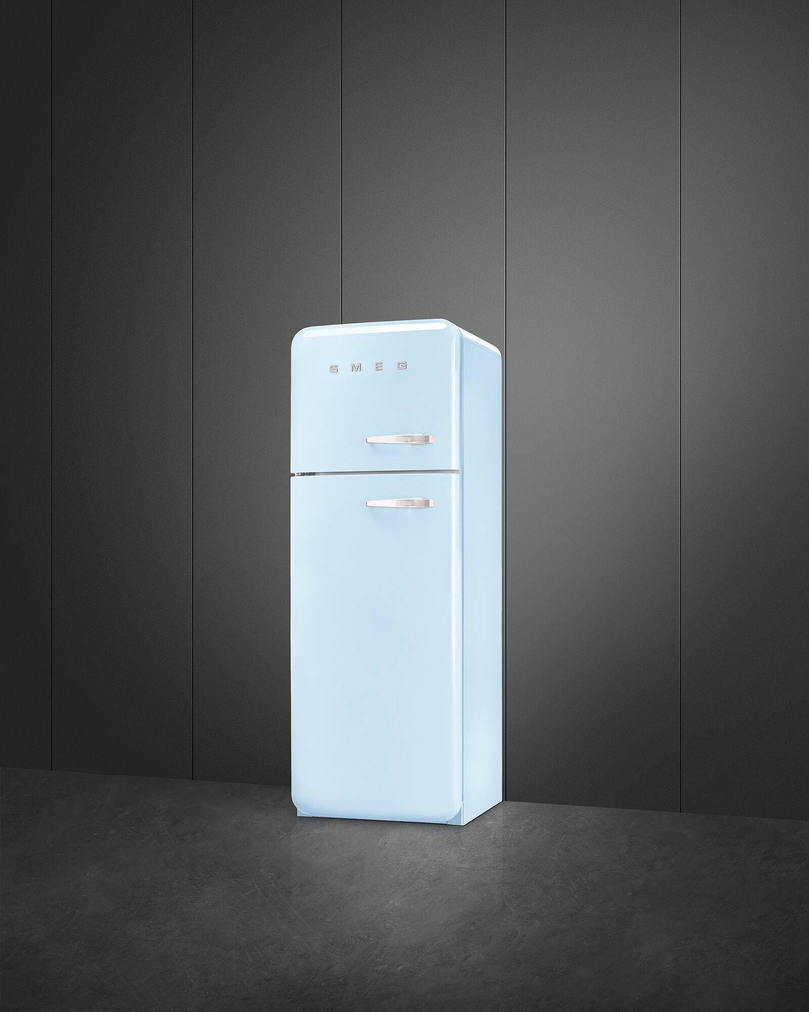 Ein hellblauer SMEG-Kühlschrank steht auf einem dunklen Boden vor einer dunkelgrauen Wand. Es ist sauber und modern.