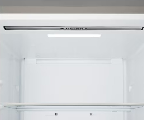 Wnętrze pustej, białej lodówki. Na górze napis 'Door Cooling+'. Widoczna półka i światło.