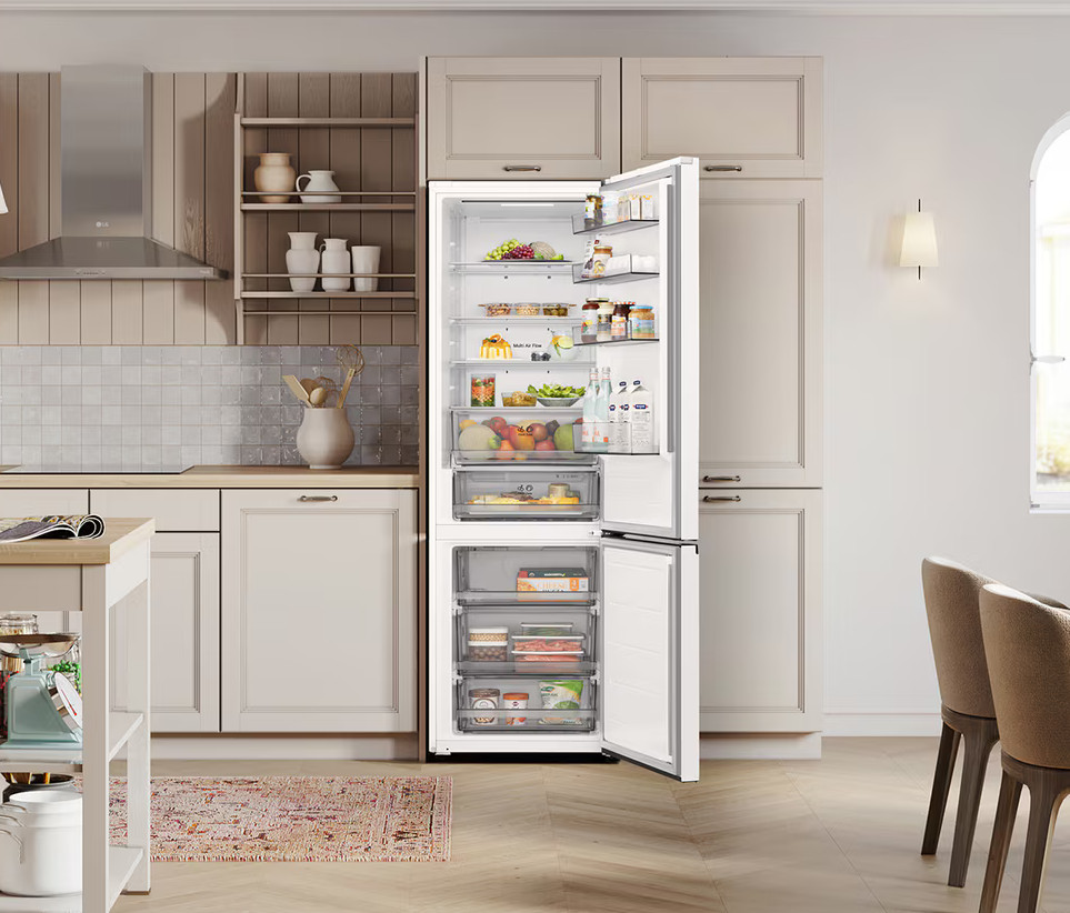 Otwarta lodówka w kuchni. Pełna jedzenia. Beżowe szafki, drewniana podłoga i dywan na podłodze. Dwa krzesła po prawej.