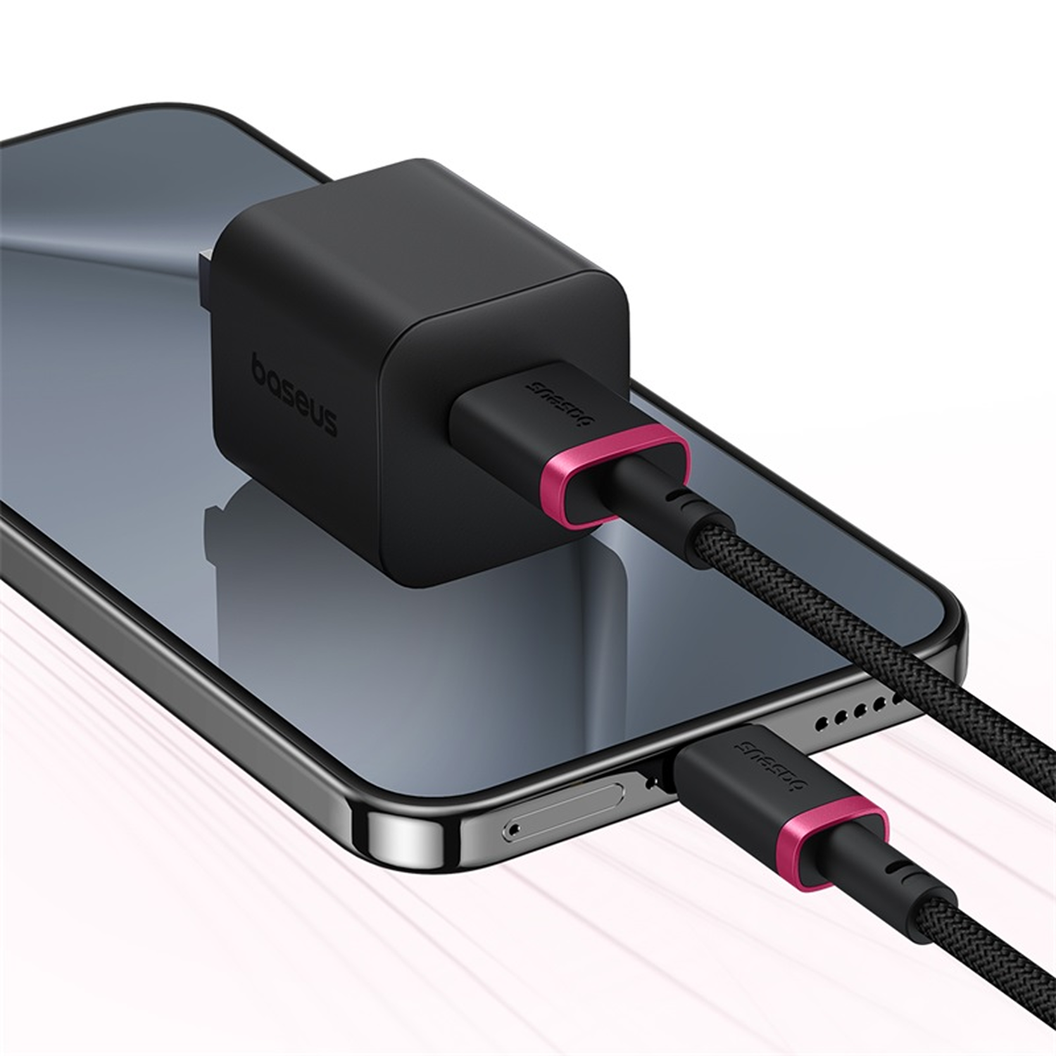 Un cargador Baseus negro está conectado a un teléfono. El cargador tiene un acento rosa y el teléfono es negro. Un cable de carga es visible.
