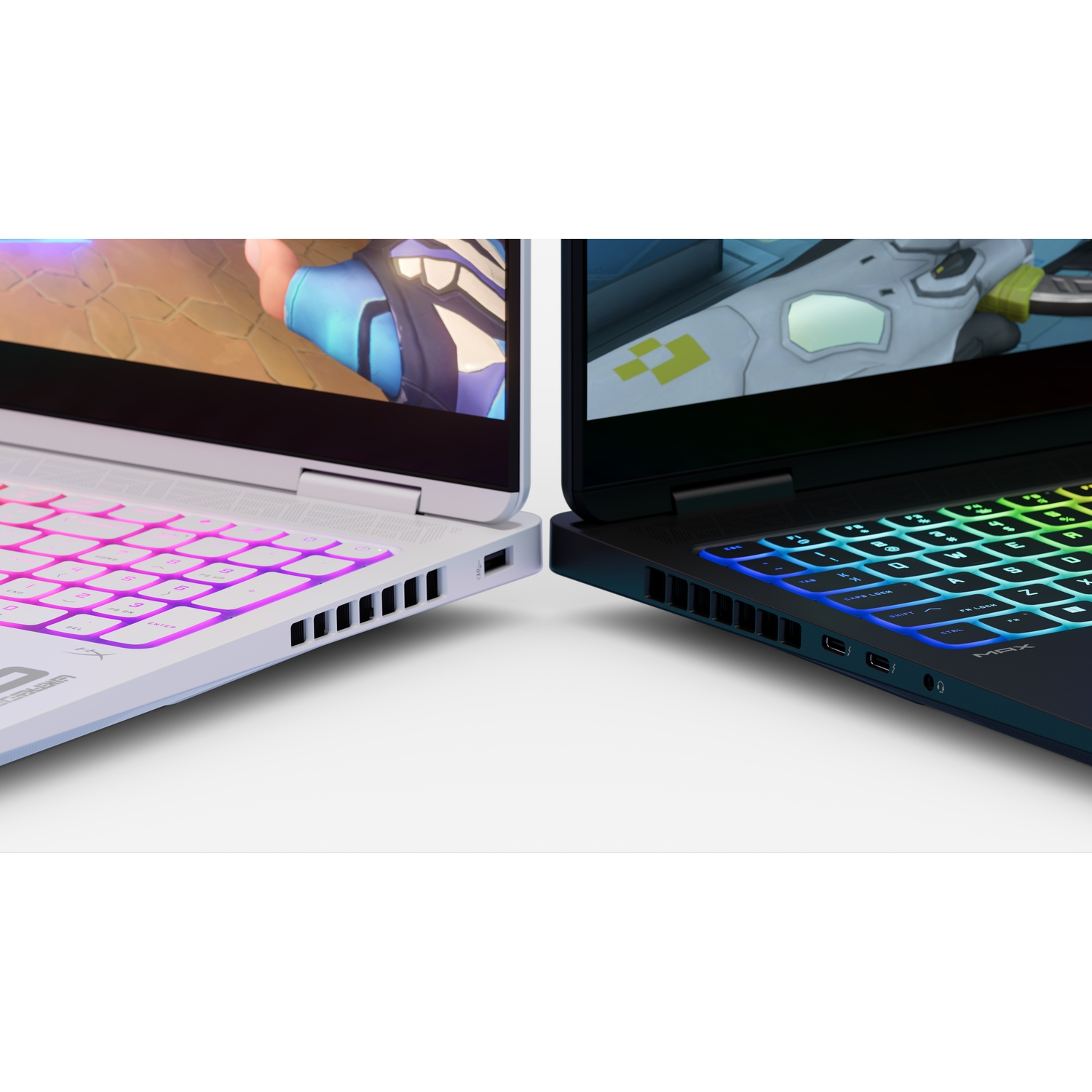 Two laptops side by side. One white with pink keyboard, the other black with rainbow keyboard, screens showing game graphics.