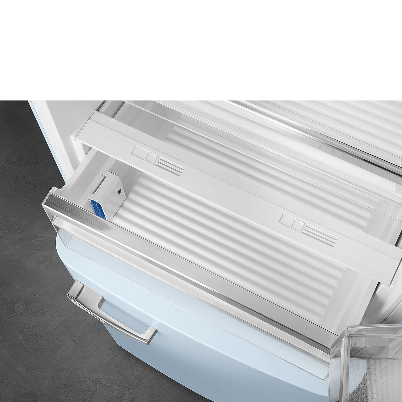 Offene Kühlschublade. Hellblauer Kühlschrank mit silberner Verkleidung. Weißer Innenraum mit blau-weißem Wasserspender.
