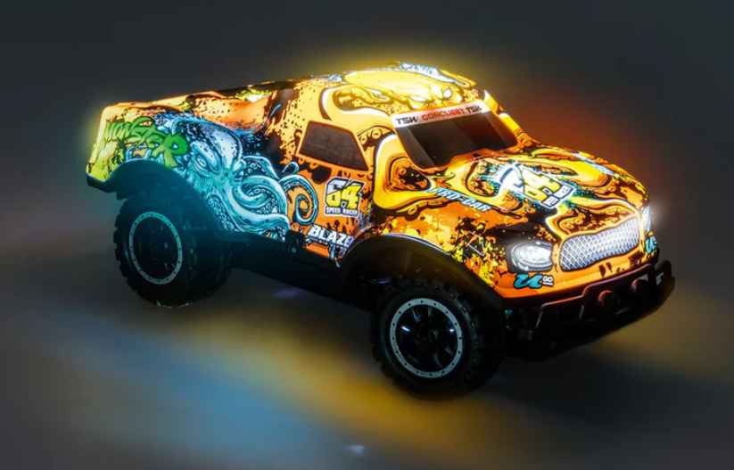 Ein Spielzeug-Monstertruck mit orange-schwarzem Design, einem Oktopus-Motiv, beleuchteten Scheinwerfern und dunklem Hintergrund.