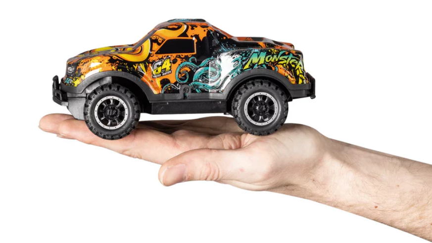 Ein Spielzeug-Monstertruck wird in einer Hand gehalten. Er ist orange und schwarz und hat große Reifen. Der Hintergrund ist weiß.