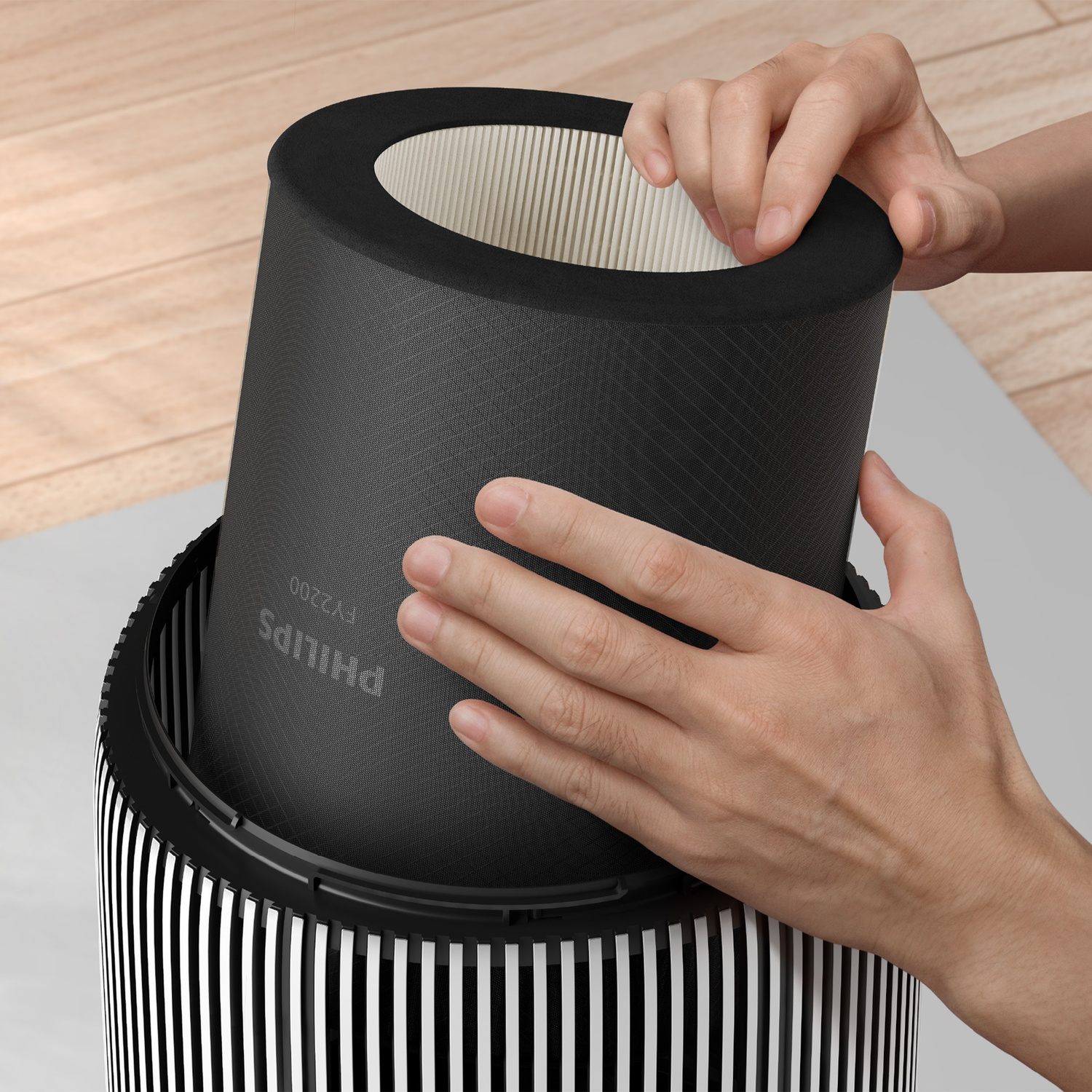 Hands placing a black air filter cartridge into a striped air purifier. The filter has the brand name 'Philips' on it.