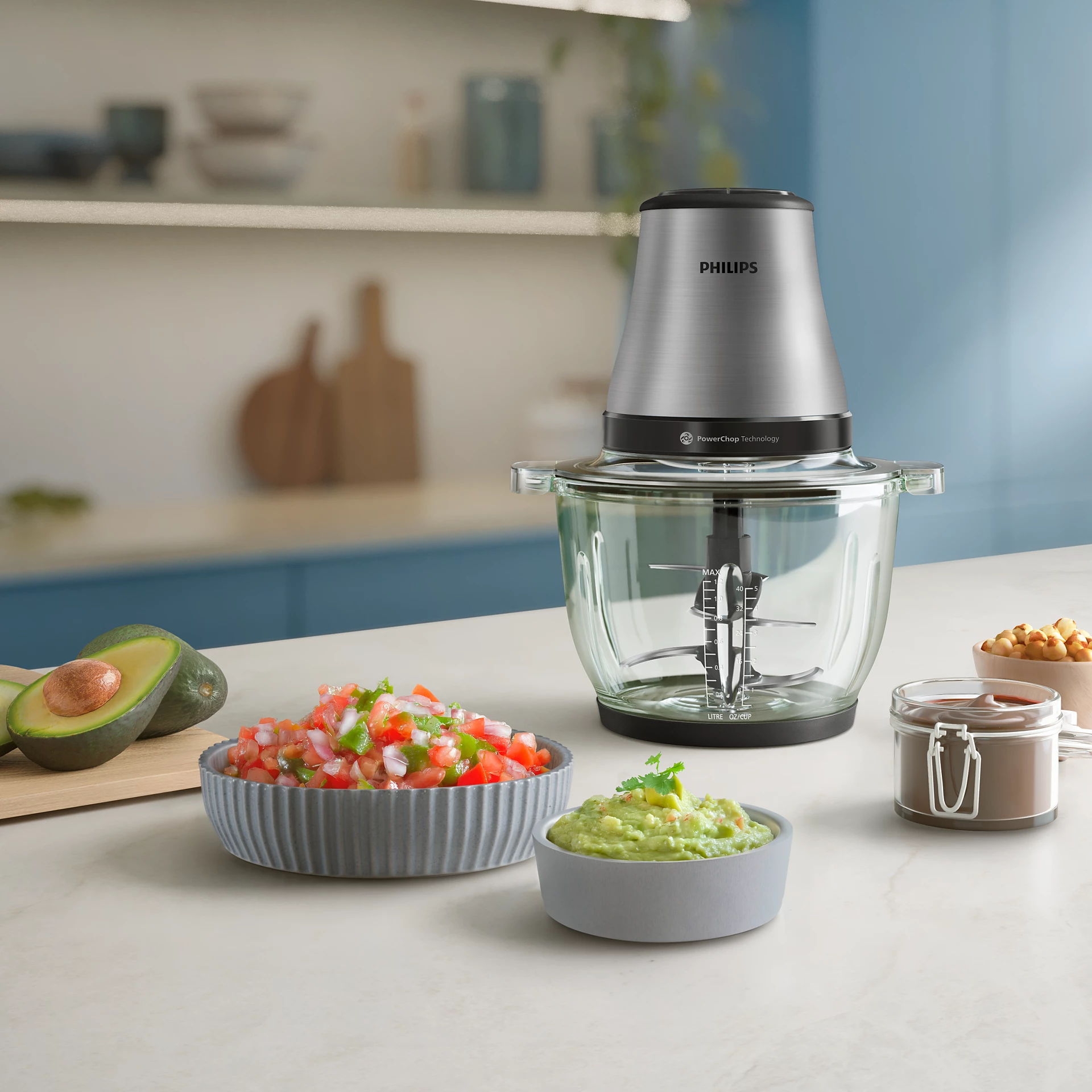 Procesador de alimentos con salsa, guacamole y aguacates. Ingredientes en la encimera. Fondo azul claro.