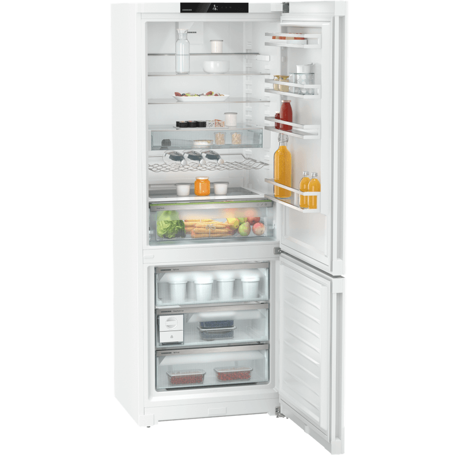 Open white refrigerator filled with food: fruits, vegetables, juice bottles, jars, and containers on shelves and drawers.
