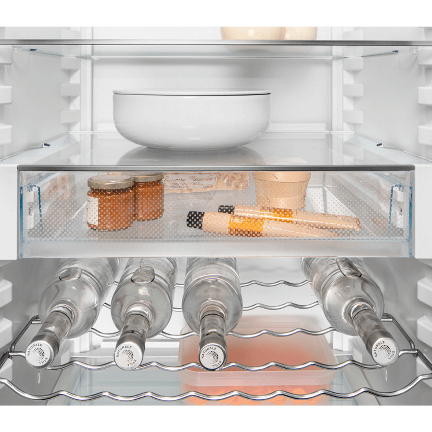 Inside a fridge: white bowl, jars, food items, bottles, and a container. Clear glass shelves and metal racks are visible.
