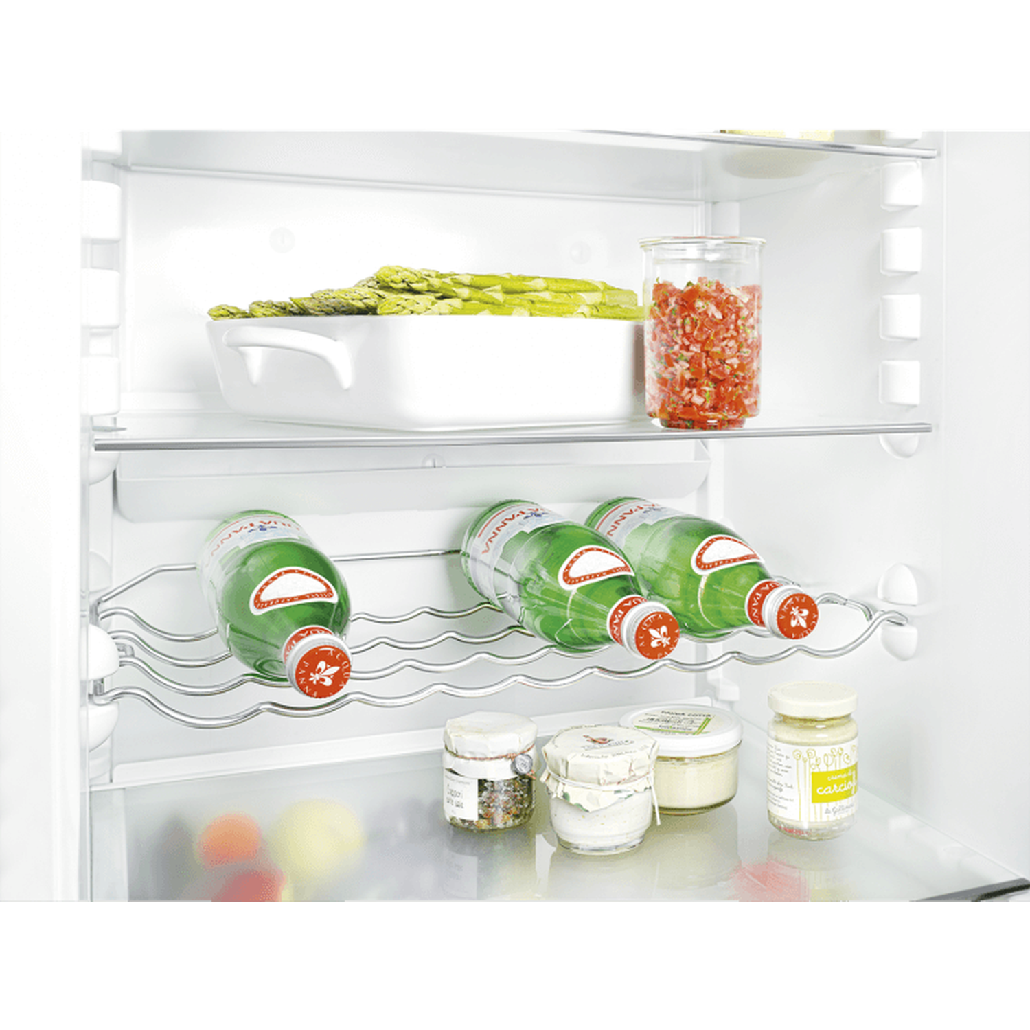 Inside a fridge: bottles, jar with tomatoes, asparagus, and jars with different sauces.