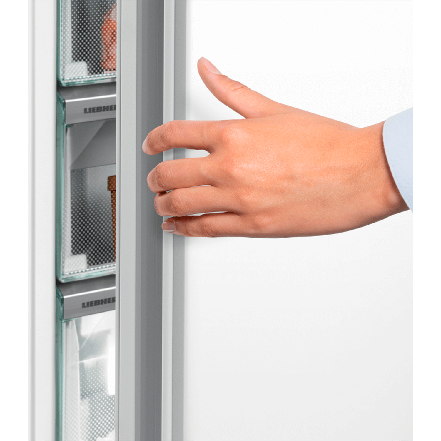 A hand opens a refrigerator door. The fridge has glass shelves and the brand name 'LIEBHERR' is visible.