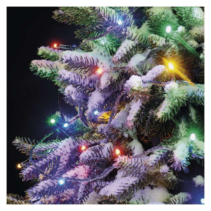 Hókristályos karácsonyfa közelről színes fényekkel. A háttér sötét.
