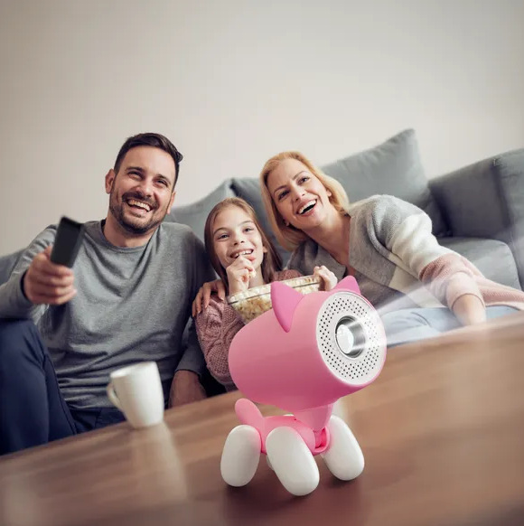 Rodzina ogląda telewizję, uśmiechając się. Różowy projektor w kształcie psa na stole. Mężczyzna z pilotem, dziewczyna z popcornem, kobieta. Sofa.