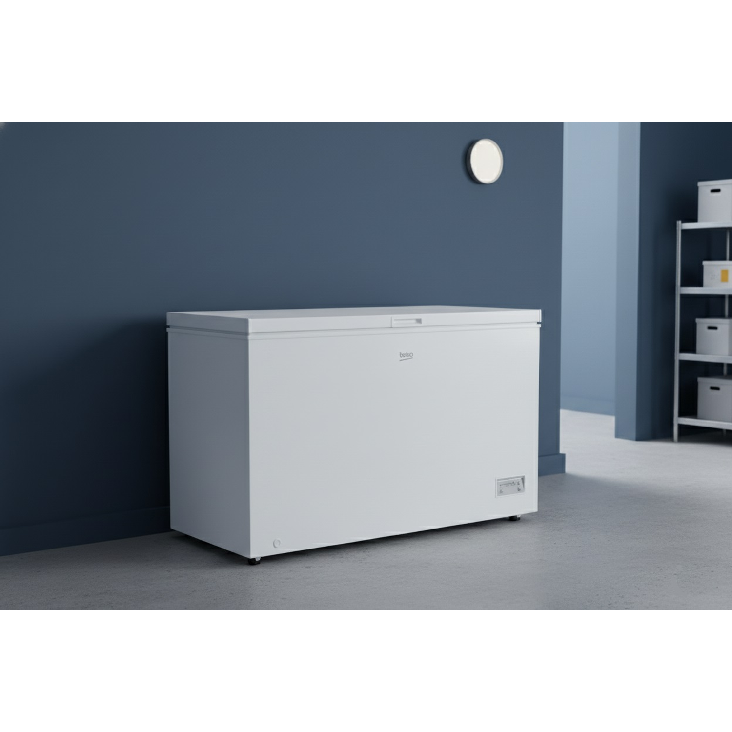 A white Beko chest freezer stands against a dark blue wall. A round mirror hangs above it. A shelf unit is on the right.