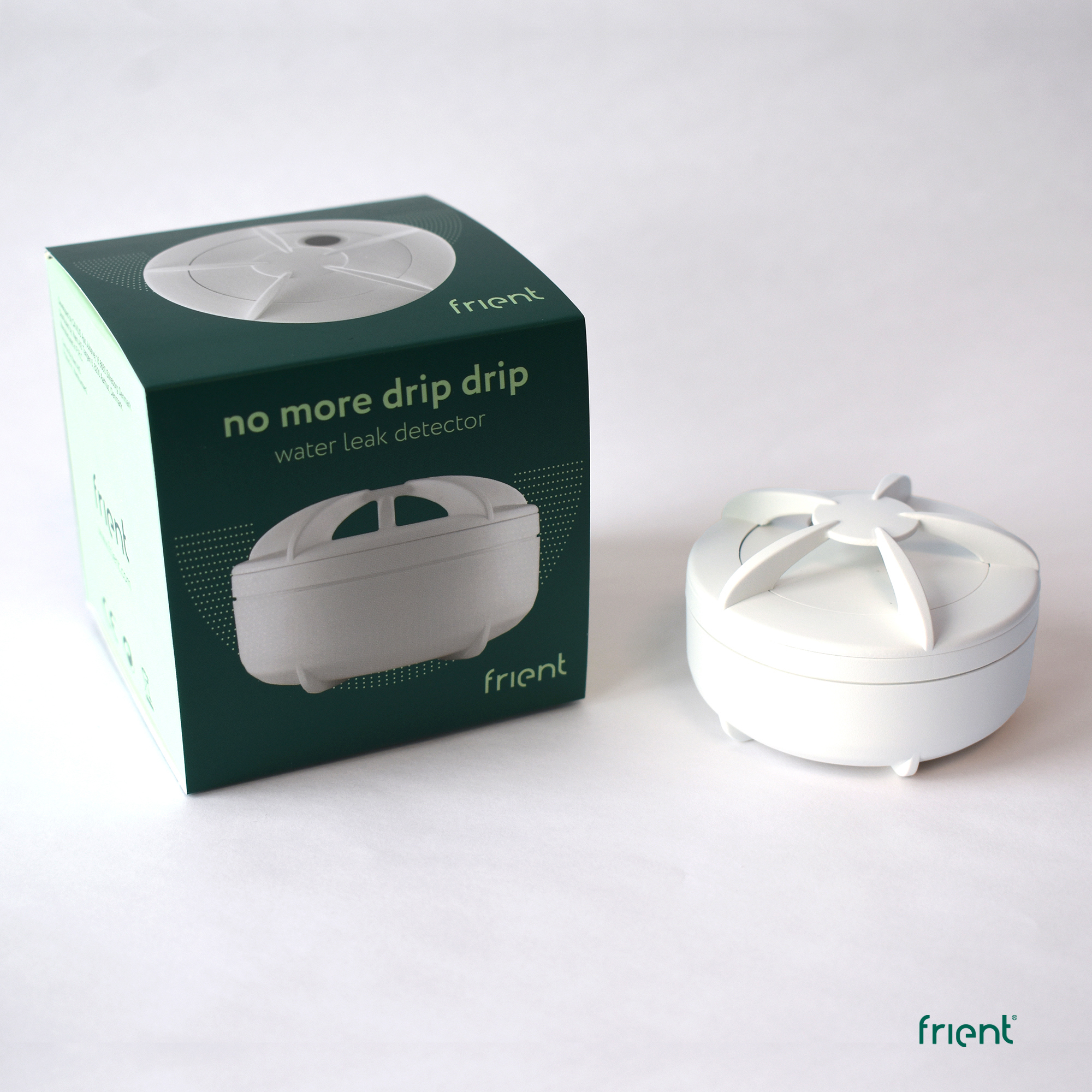Ein weißer Wasserleckdetektor und seine grüne Box. Auf der Box steht 'no more drip drip water leak detector' und die Marke 'frient'.