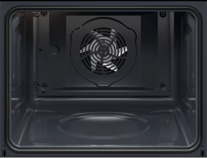 Innenansicht eines dunklen Ofens. Hinten ist ein Ventilator zu sehen, der von einem Metallrahmen umgeben ist. Der Innenraum ist dunkel und leer.