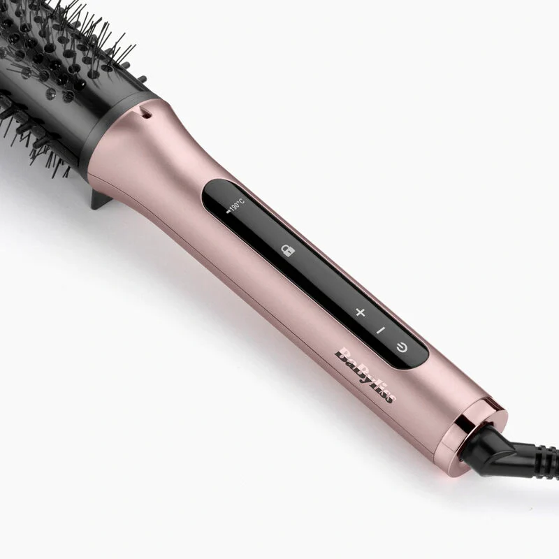 Spazzola per lo styling dei capelli oro rosa su bianco. Ha un manico nero con bottoni e una testa a setole nere.