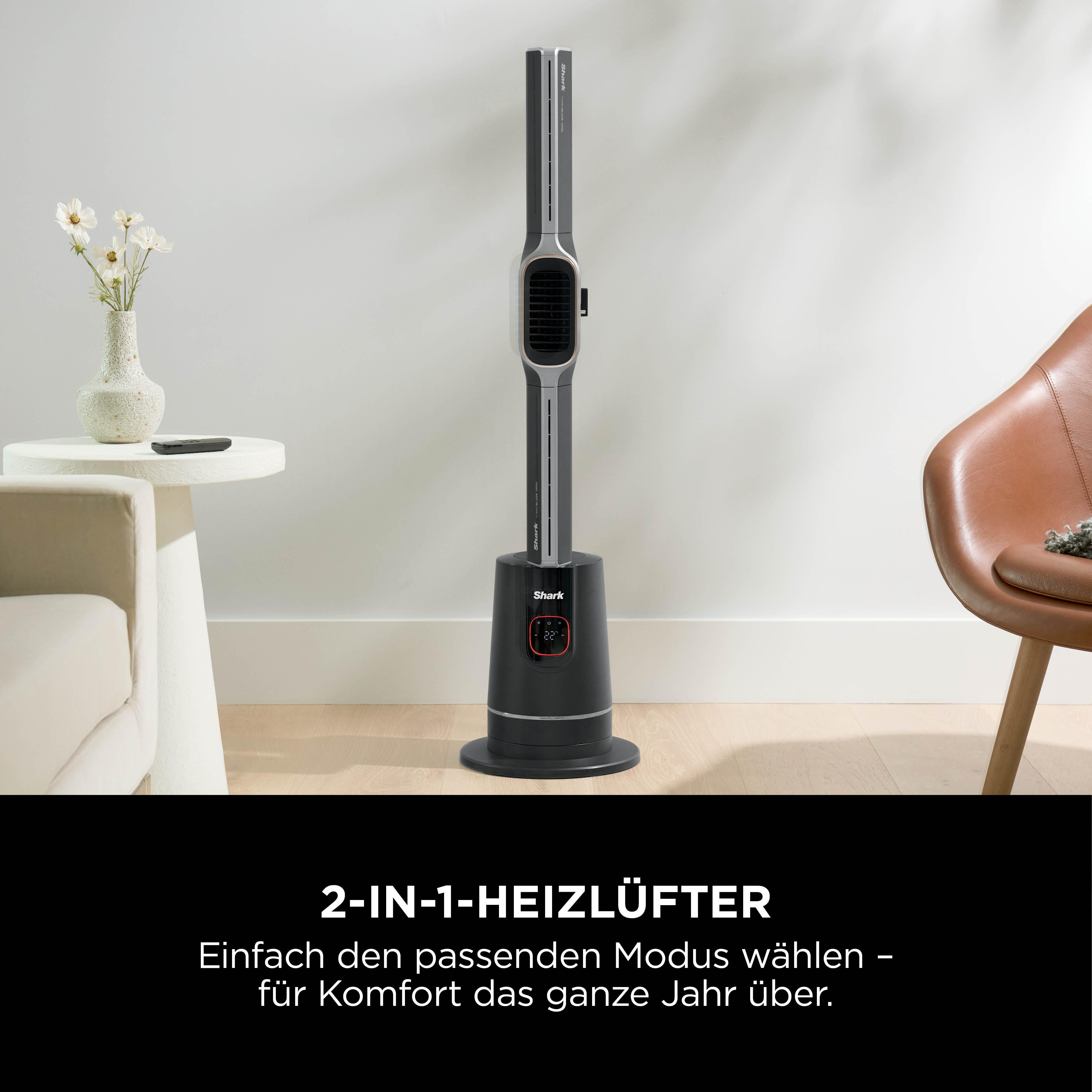 Ein schwarzer und grauer Shark-Ventilator steht in einem Raum. Ein Tisch und ein Stuhl sind im Hintergrund.