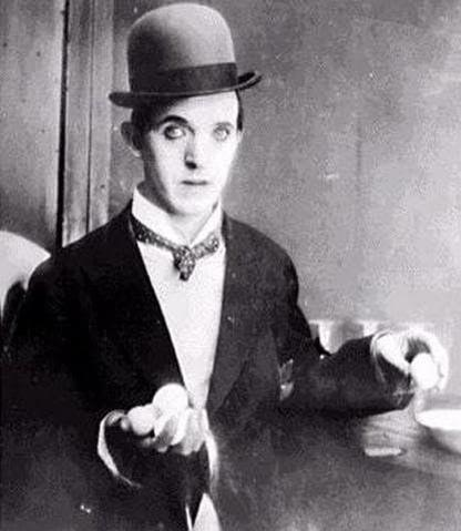 Ein Mann mit Melone und Anzug hält Eier. Er hat dunkles Augen-Make-up und eine gemusterte Krawatte. Vintage Schwarz-Weiß-Foto.