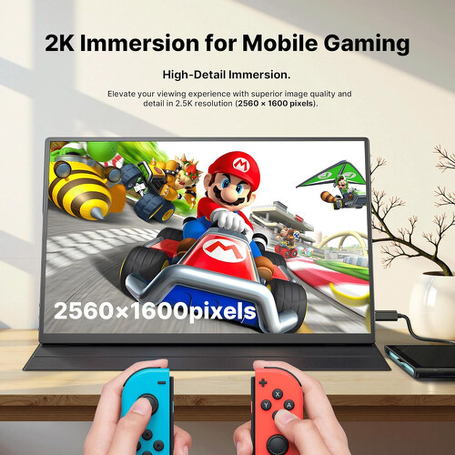 Hands holding game controllers, displaying a 2K monitor with a racing game scene featuring Mario. Text indicates 2560x1600 resolution.
