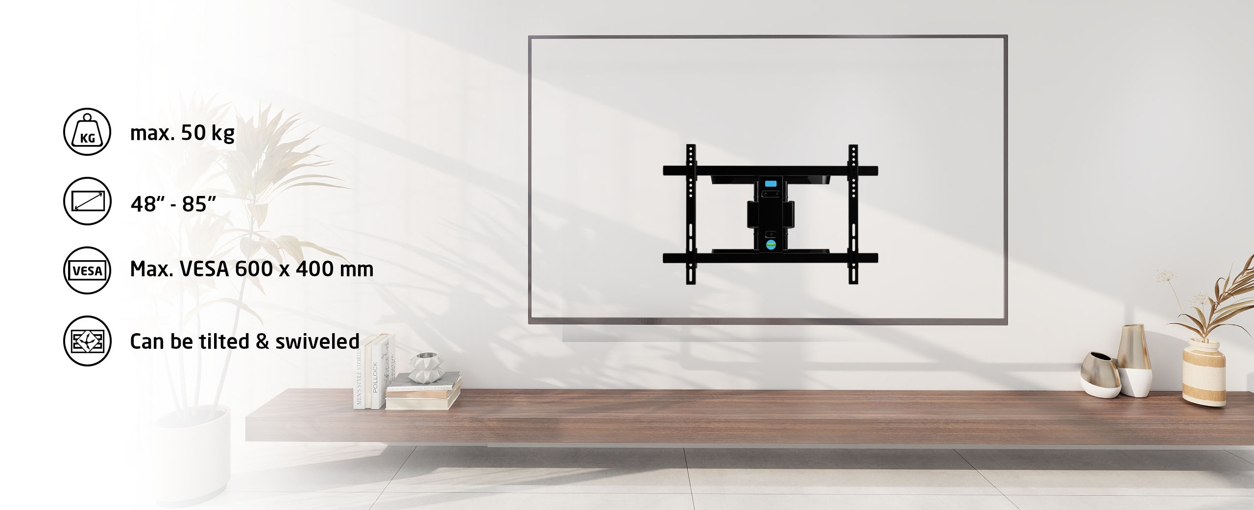 Czarny uchwyt do TV na białej ścianie. Nad drewnianą półką z elementami dekoracyjnymi. Tekst pokazuje max. 50 kg i inne specyfikacje.