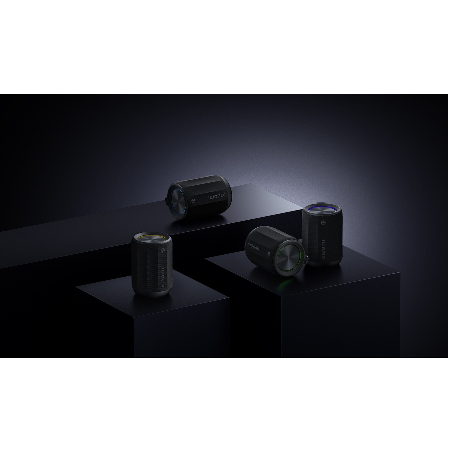 Four black cylindrical speakers on black platforms. Each has a metallic top and the Xiaomi logo. The background is dark.