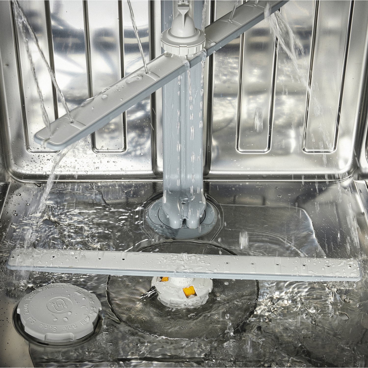 Inside a dishwasher, water sprays from rotating arms. The interior is stainless steel, with a filter and a salt container visible.