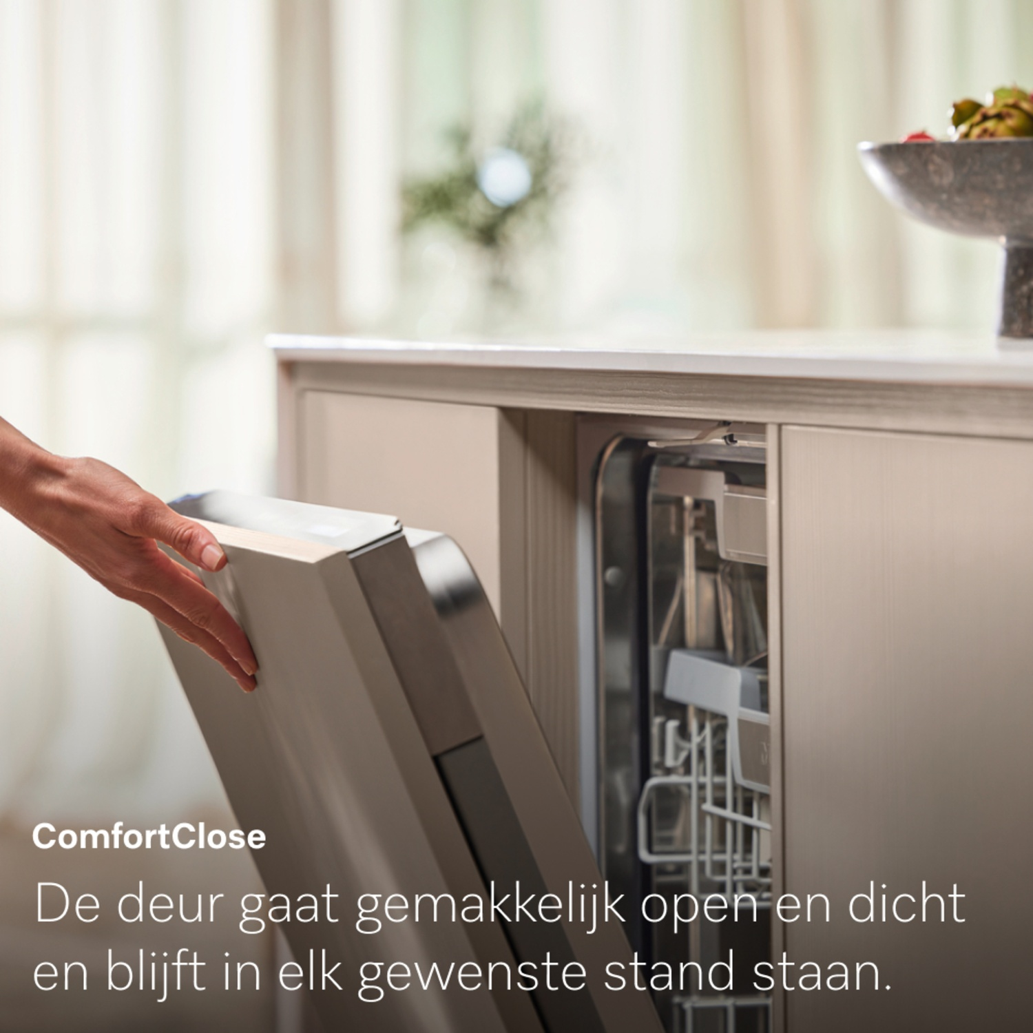 A hand opens a dishwasher door. The dishwasher is built into a kitchen cabinet. The text 'ComfortClose' is visible.