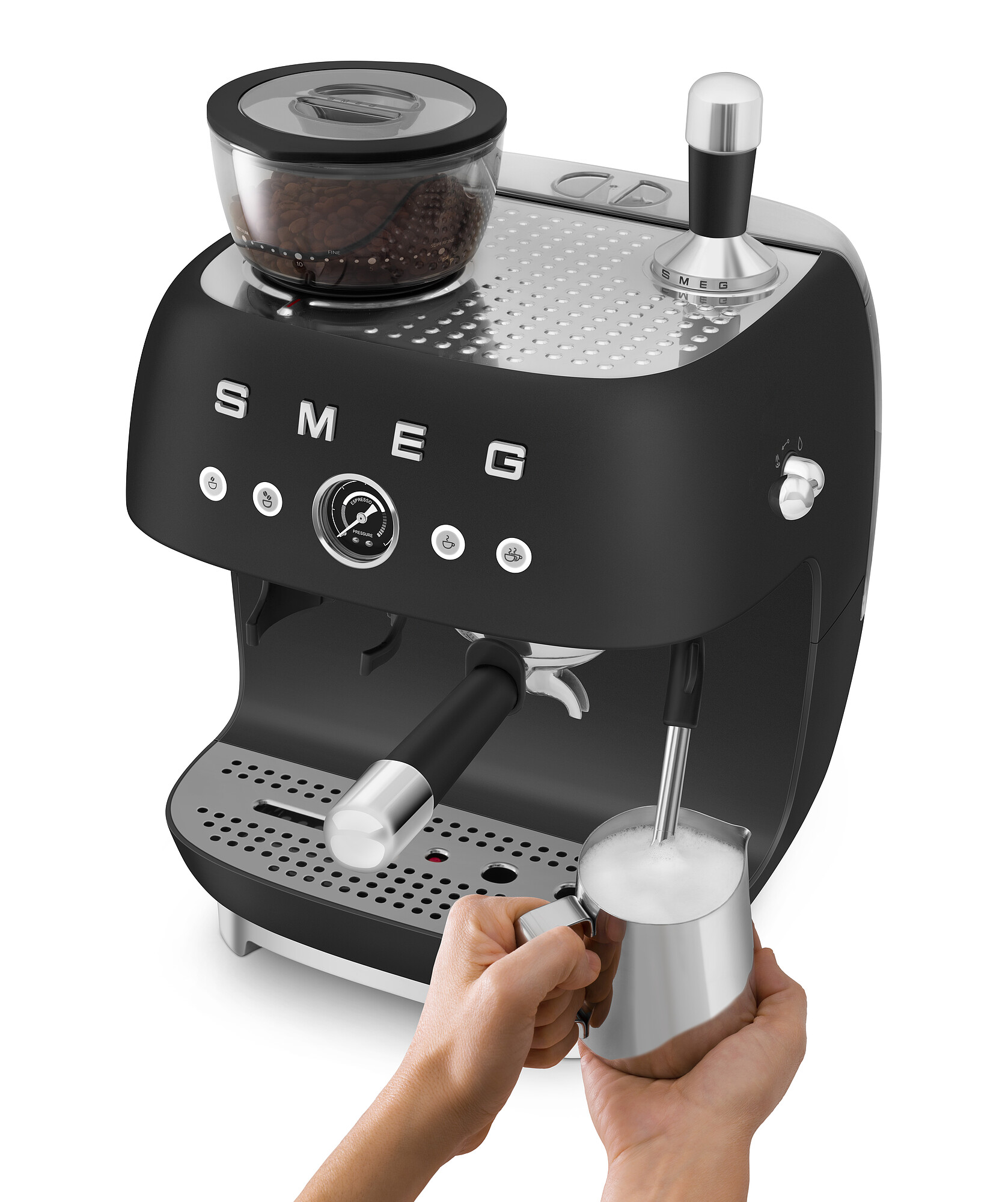 Schwarze SMEG Espressomaschine mit Milchaufschäumer. Hände halten einen silbernen Krug mit aufgeschäumter Milch.