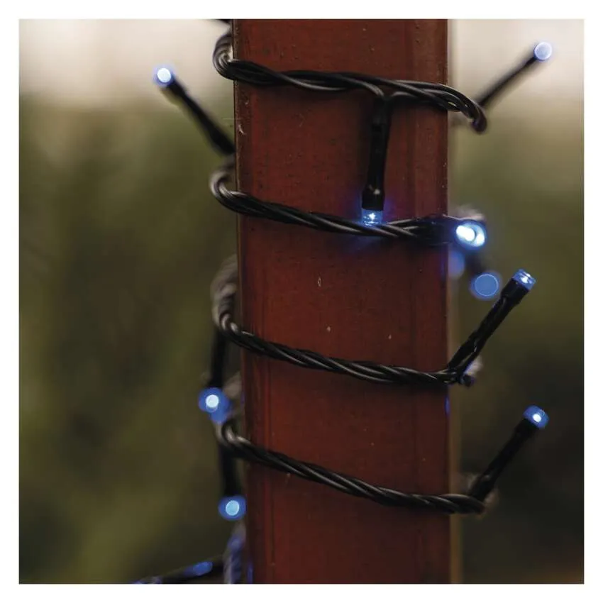 Kék LED-es füzérfények egy barna oszlop köré tekerve. Fekete vezeték tartja a lámpákat. A háttér elmosódott zöld.